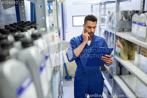 Image of auto mechanic calling on smartphone at car shop