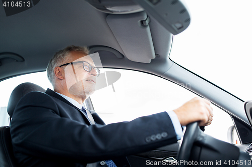 Image of happy senior businessman driving car