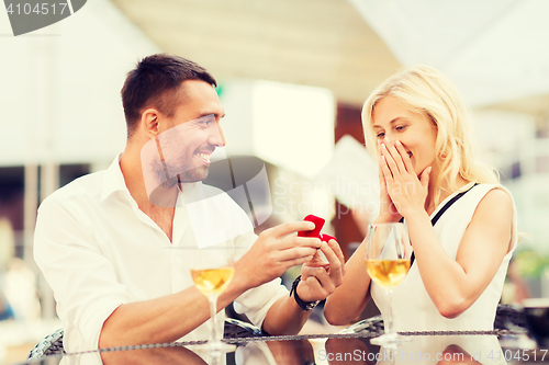 Image of happy couple with engagement ring and wine at cafe