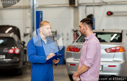 Image of auto mechanic with clipboard and man at car shop