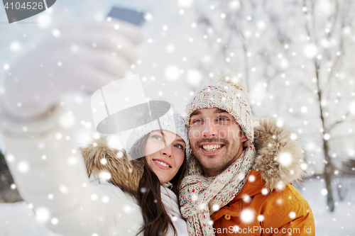 Image of happy couple taking selfie by smartphone in winter