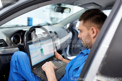 Image of mechanic man with laptop making car diagnostic