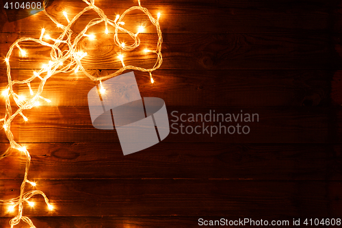 Image of Dark brown wooden background with shining garland on the left
