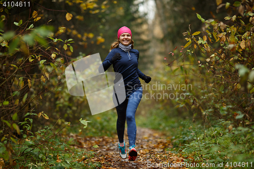 Image of Portrait in full growth of sporty woman jogging in park