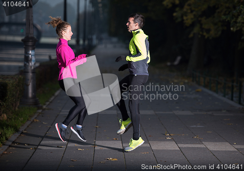 Image of a young couple warming up before jogging