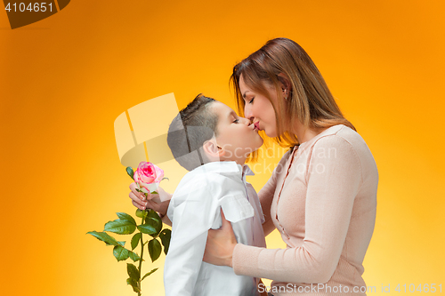 Image of Young kid giving red rose to his mom