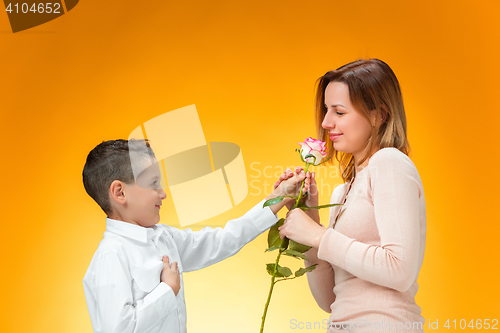 Image of Young kid giving red rose to his mom