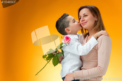 Image of Young kid giving red rose to his mom