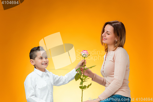 Image of Young kid giving red rose to his mom