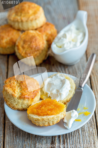 Image of Scones with orange jam and whipped cream for breakfast.