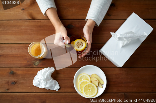 Image of ill woman drinking tea with lemon and ginger