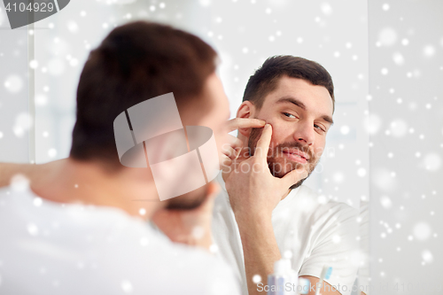 Image of man squeezing pimple at bathroom mirror