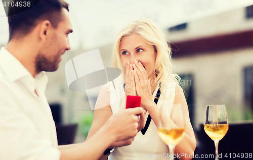 Image of happy couple with engagement ring and wine at cafe