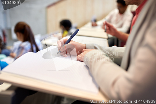 Image of student writing to notebook at exam or lecture