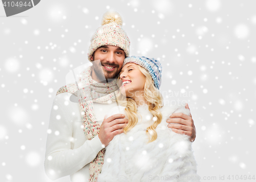 Image of smiling couple in winter clothes hugging over snow