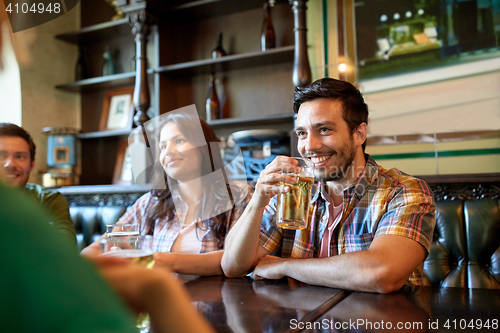 Image of happy friends drinking beer at bar or pub