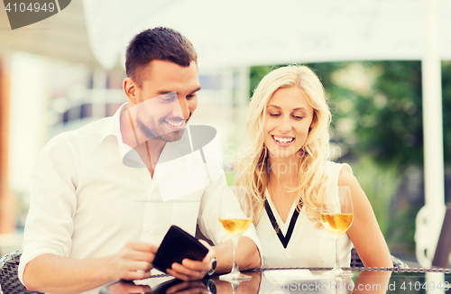 Image of happy couple with wallet and bill at restaurant