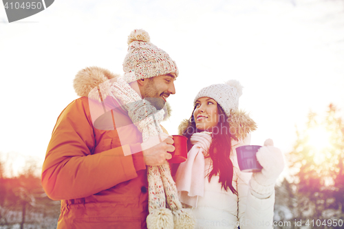 Image of happy couple with tea cups over winter landscape