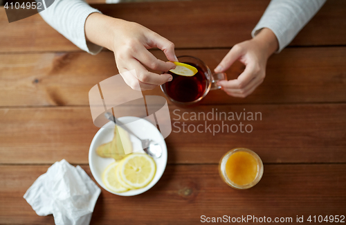 Image of close up of woman adding lemon to tea cup