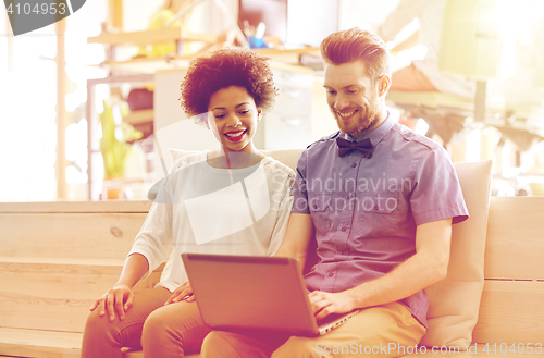 Image of happy creative team with laptop in office