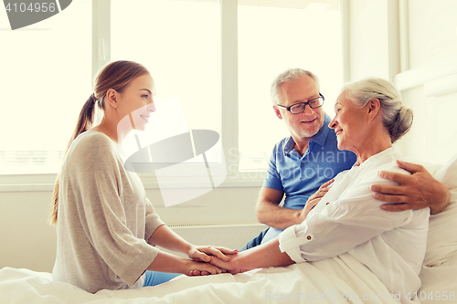 Image of happy family visiting senior woman at hospital