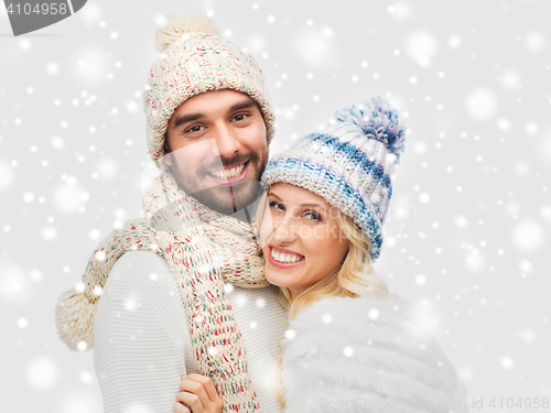 Image of smiling couple in winter clothes hugging over snow