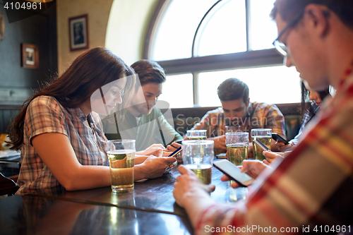 Image of friends with smartphones and beer at bar or pub