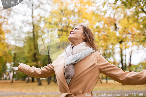 Image of beautiful happy young woman walking in autumn park