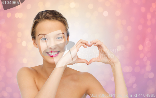 Image of smiling young woman showing heart shape hand sign