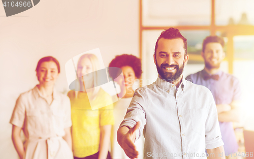 Image of happy man making handshake over office team
