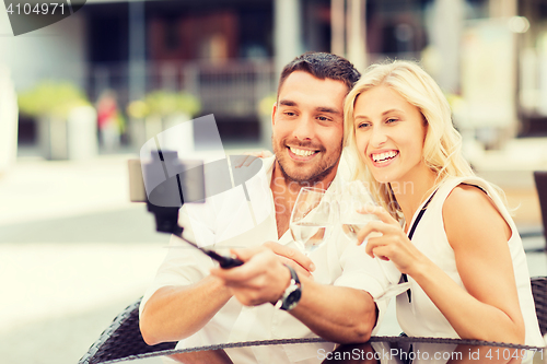 Image of happy couple taking selfie with smartphone at cafe