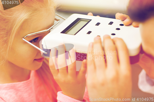 Image of optician with pupillometer and girl at eye clinic