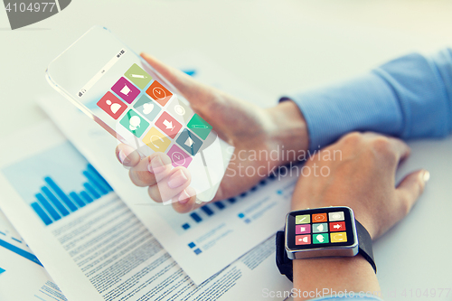 Image of close up of hands with smart phone and watch icons