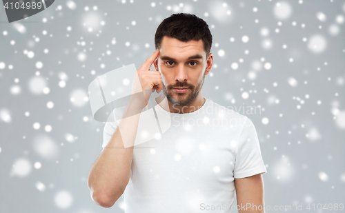 Image of man with finger at temple over snow background