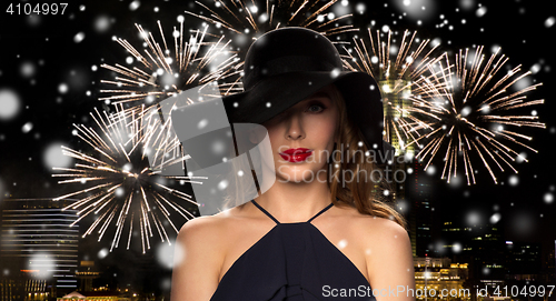Image of beautiful woman in black hat over night firework