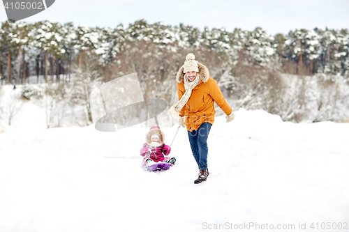 Image of happy father pulling sled with child in winter