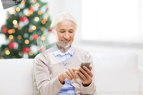 Image of senior woman with smartphone texting at christmas