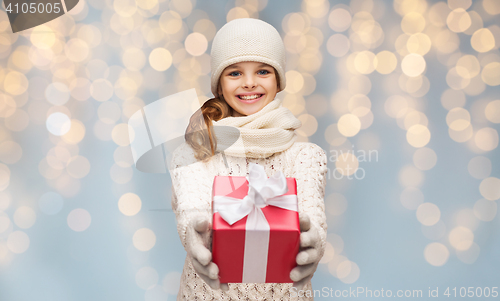 Image of smiling girl in winter clothes with christmas gift