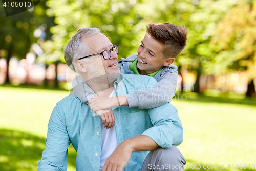 Image of grandfather and grandson hugging at summer park