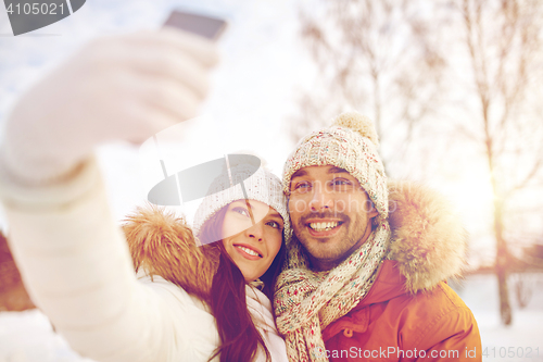 Image of happy couple taking selfie by smartphone in winter