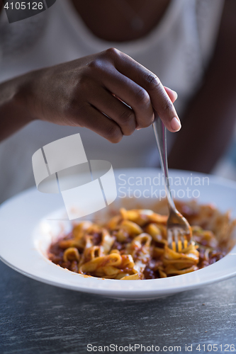 Image of a young African American woman eating pasta