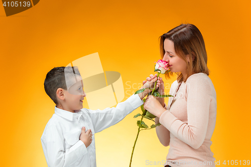 Image of Young kid giving red rose to his mom