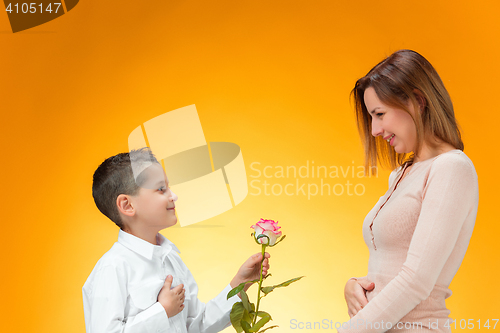 Image of Young kid giving red rose to his mom