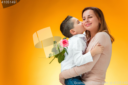 Image of Young kid giving red rose to his mom