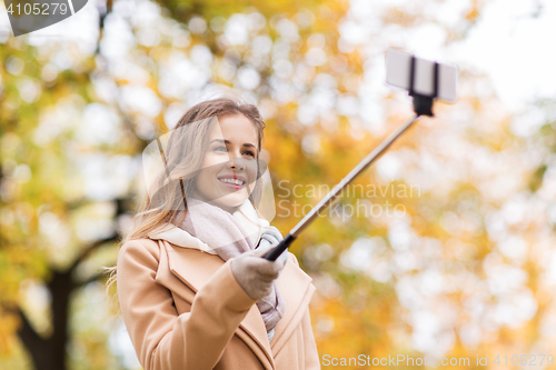 Image of woman taking selfie by smartphone in autumn park