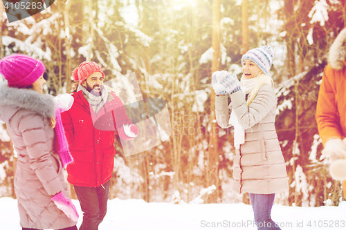 Image of happy friends playing snowball in winter forest