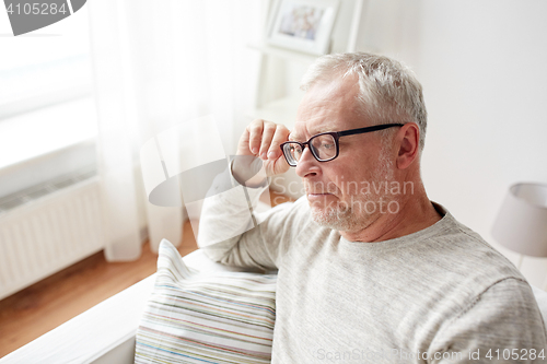 Image of  senior man sitting on sofa at home and thinking