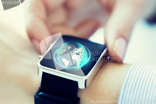 Image of close up of hand with globe hologram on smartwatch