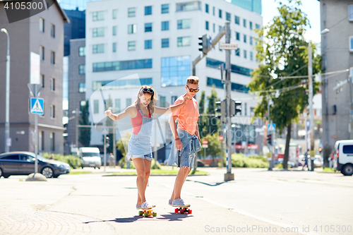 Image of teenage couple riding skateboards on city street