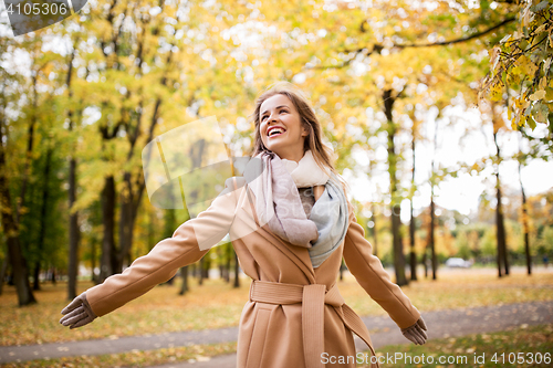 Image of beautiful happy young woman walking in autumn park